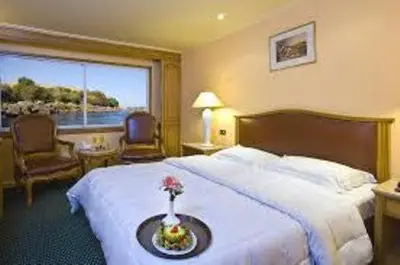 a hotel room with a bed and a large window at Ultra Nile Cruise 5 Star Luxor To Aswan in Luxor