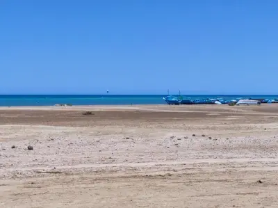 a sandy beach with a boat in the water at Boka Bay One in Hurghada