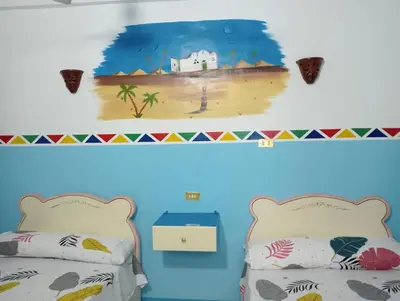 a bedroom with two beds and a painting of a beach at Sabaha Kato in Aswan