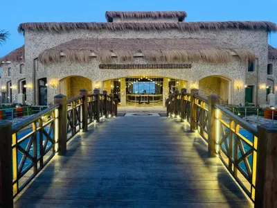 a boardwalk leading to a building with a restaurant at Amarina Jannah Resort & Aqua Park Marsa Alam in Coraya Bay