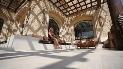 a woman sitting on a bench in front of a building at Amarina Jannah Resort & Aqua Park Marsa Alam in Coraya Bay