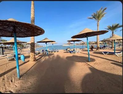 a beach with umbrellas and chairs and the ocean at Family Suite in view aqua mirage bay in Hurghada