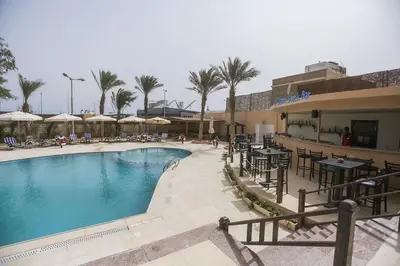 a swimming pool with tables and chairs in a resort at Jawhara Inn Hotel - فندق الجوهرة سفاجا in Hurghada