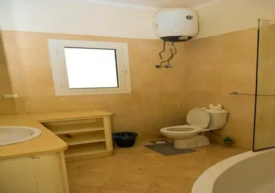 a bathroom with a toilet and a sink and a window at Stylish 4BR Villa V15 with a Private Heated Pool at White Villas in Hurghada