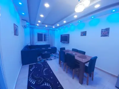 a blue room with a table and chairs and a couch at شقة ٢ غرفة in Hurghada
