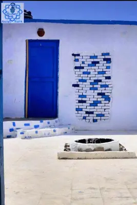 a blue door on a white building with a wall at Asilah kato nubian guest house in Aswan