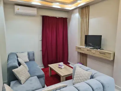 a living room with two blue couches and a tv at Hurghada Appartment front of dream beach in Hurghada