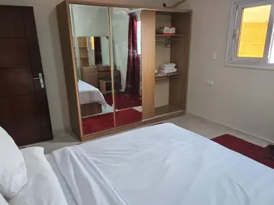 a bedroom with a white bed and a mirror at Hurghada Appartment front of dream beach in Hurghada