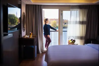 a woman looking out the window of a hotel room at ToBadaa - Nile cruise all inclusive from Aswan or Luxor 4 Days & 7 days in Aswan