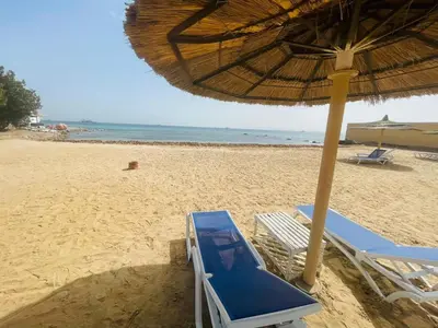 a beach with chairs and an umbrella on the sand at Navy Chalets 107 in Hurghada