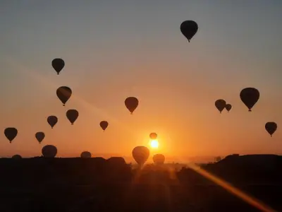 a group of hot air balloons flying in the sunset at The royal flat for rent in Al Qurnah