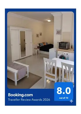 a living room with a table and chairs and a kitchen at Nice Studio in Elegant Compound Intercontinental Area in Hurghada