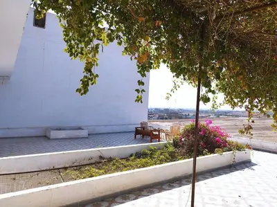 a bench next to a white building with flowers at Gabawy Garden Doppelzimmer in Luxor