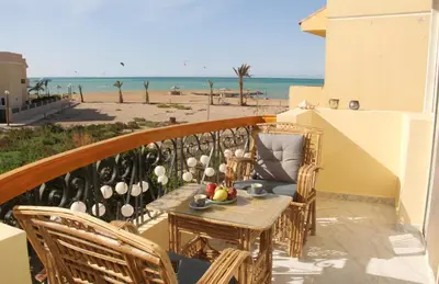 a table on a balcony with a view of the beach at Villa Anna & Snake in Hurghada