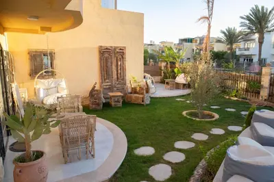 a backyard with chairs and tables and a lawn at Villa Anna & Snake in Hurghada