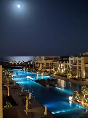 a large pool with blue lights at night at Mangroovy 1br Charming Escape Hilton pool view in Hurghada