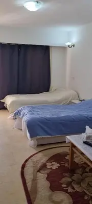 a bedroom with two beds and a table with a rug at Palma Resort in Hurghada